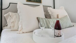 A bed with white bedding, a bottle of wine, and two glasses on a tray. - Oak Valley | King Bed, Sun Deck & Outdoor Shower, Full Kitchen, Fire-pit (Fredericksburg)