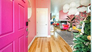 A hallway with a pink door, patterned wallpaper, a wooden floor, and a Christmas tree with decorations. - The Audacity Boise - BSU -Close to eveything ! (Boise)
