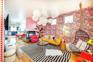 A modern living room with a sofa, chairs, a dining area, and a kitchen in the background.