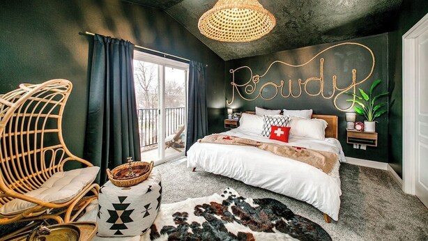 A bedroom with a bed, a wicker chair, a bedside table, a wall-mounted lamp, and a large window. - The Audacity Boise - BSU -Close to eveything ! (Boise)