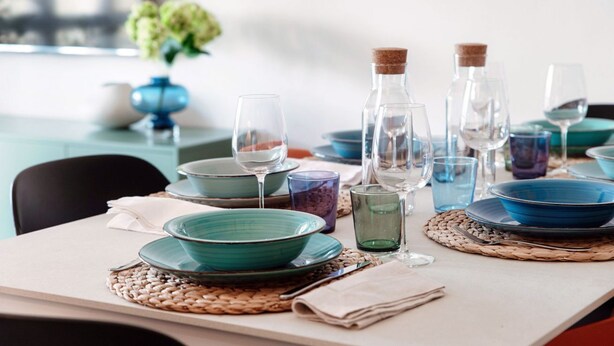 A dining table set with blue plates, clear glasses, and a woven placemat. - Como Hills - MyHomeinComo (Como)