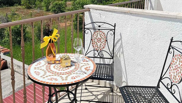 Un balcon avec une table ronde et deux chaises, offrant une vue sur un paysage magnifique.