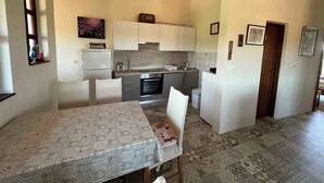 Une cuisine compacte dotée d’appareils électroménagers modernes, un coin repas avec une nappe à motifs et un sol à motifs.