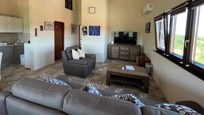 Un salon avec un canapé, une table basse, un téléviseur et une fenêtre donnant sur un beau paysage.