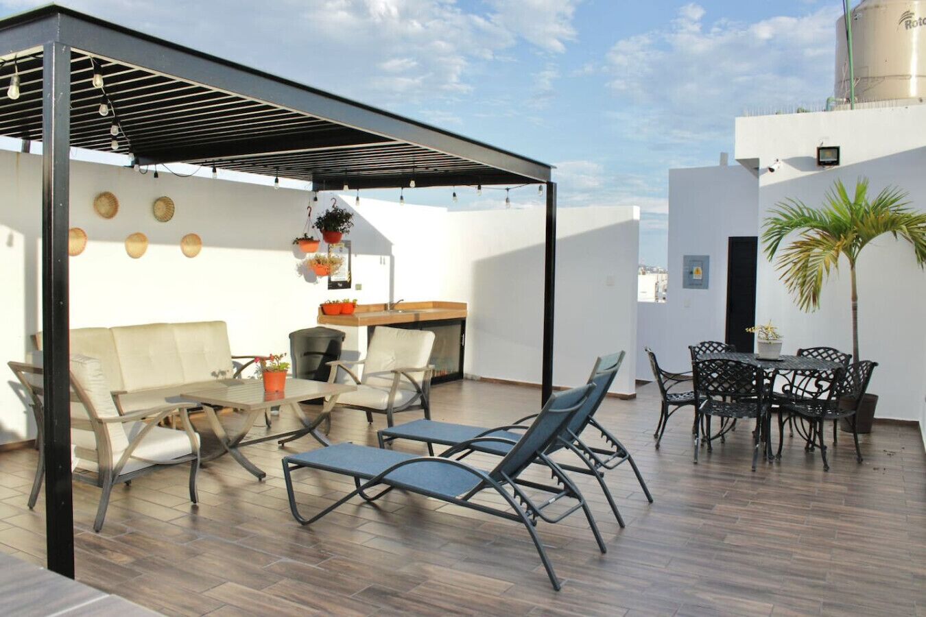 A rooftop terrace with a covered seating area, a dining table, and a small kitchen.