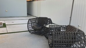 Un espace patio avec deux fauteuils en osier et une table placés sous un grand parasol.