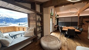 A modern interior with a wooden dining area, seating, and a view of mountains.
