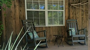 A wooden porch with two rocking chairs and a small table, surrounded by greenery. - The Cozy Cottage! Private 1-bedroom cottage in a peaceful setting in Ottsville (ottsville)