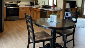A kitchen with wooden cabinets, a microwave, stove, and a dining table with chairs. - The Cozy Cottage! Private 1-bedroom cottage in a peaceful setting in Ottsville (ottsville)