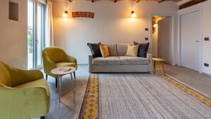 Un salon moderne avec un plafond en briques, un canapé agrémenté de coussins à motifs, un fauteuil jaune et une petite table d’appoint.