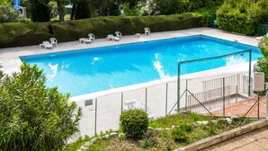 A rectangular swimming pool with a white fence, surrounded by greenery and white lounge chairs. - 2-Room Apartment with Sea View, Pool and Tennis (villeneuve loubet)