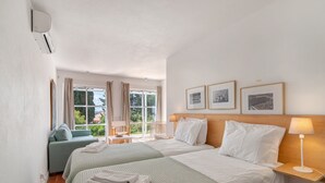 Habitación de hotel con dos camas, un sofá, un escritorio y una ventana con cortinas.