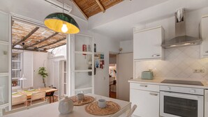 Una cocina moderna con armarios blancos, horno integrado y una zona de comedor con mesa y sillas.