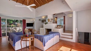 Amplia sala de estar con techo alto, chimenea y una mesa de comedor con sillas.