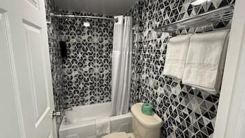 Un baño con bañera, inodoro y cortina de ducha.