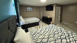 A hotel room with two beds, a television, a picture on the wall, and a door. - Beauty Rest Hotel (Edison)