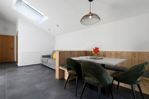 A modern interior with a high ceiling, skylight, and a dining area with green upholstered chairs and a wooden bench. - Apartment 'Lodge 3' with Mountain View, Shared Terrace and Wi-Fi (Colle Isarco)