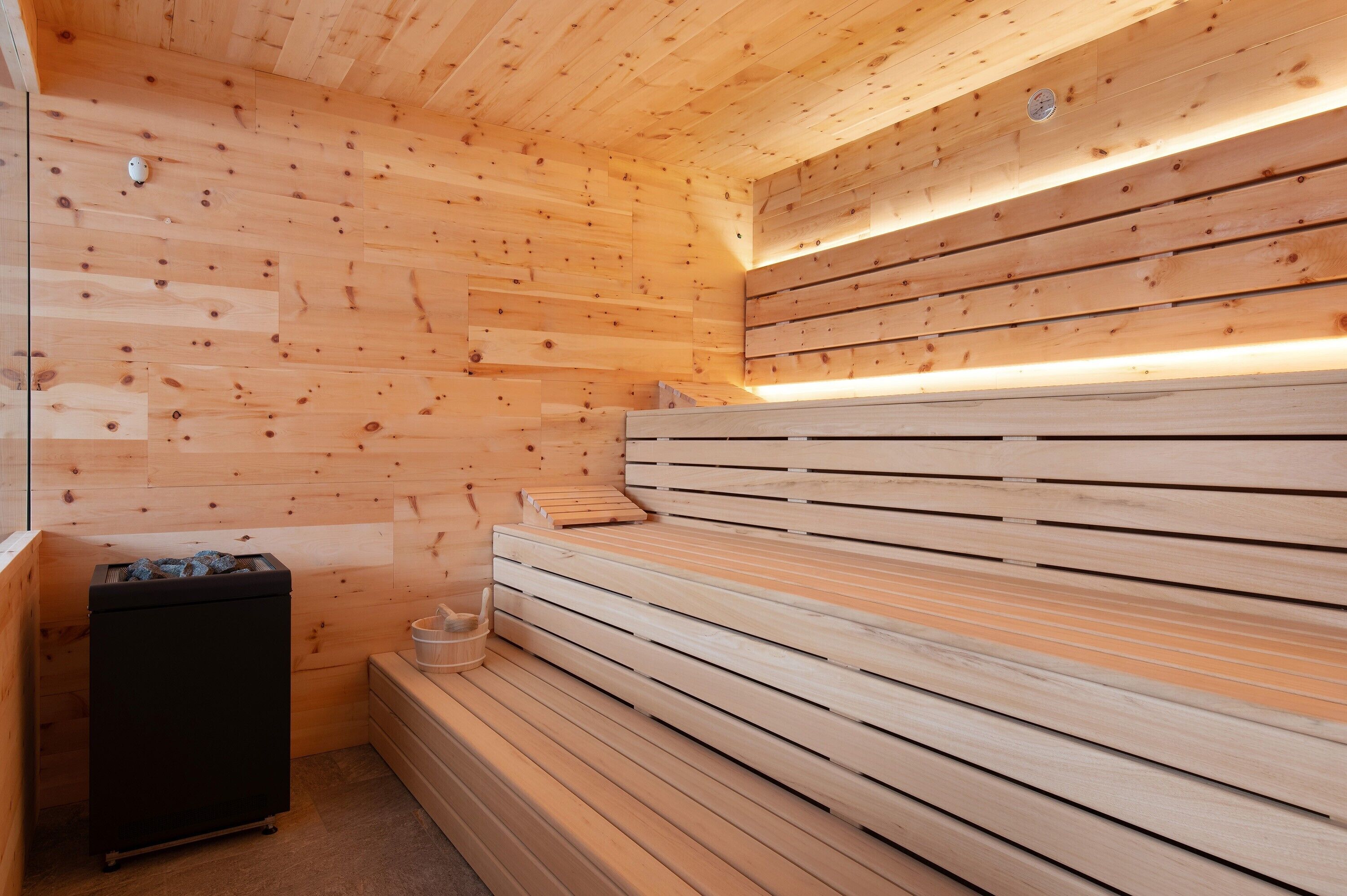A sauna with wooden benches and a black cabinet.