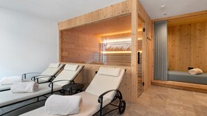 Habitación de spa con paredes de madera, dos sillas de masaje y una zona de estar pequeña con una toalla.