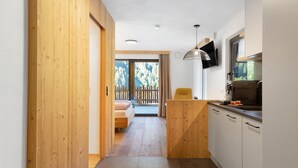 Un corridoio stretto che conduce a una camera da letto con una porta in legno, un letto e una vista su un balcone con una recinzione in legno.