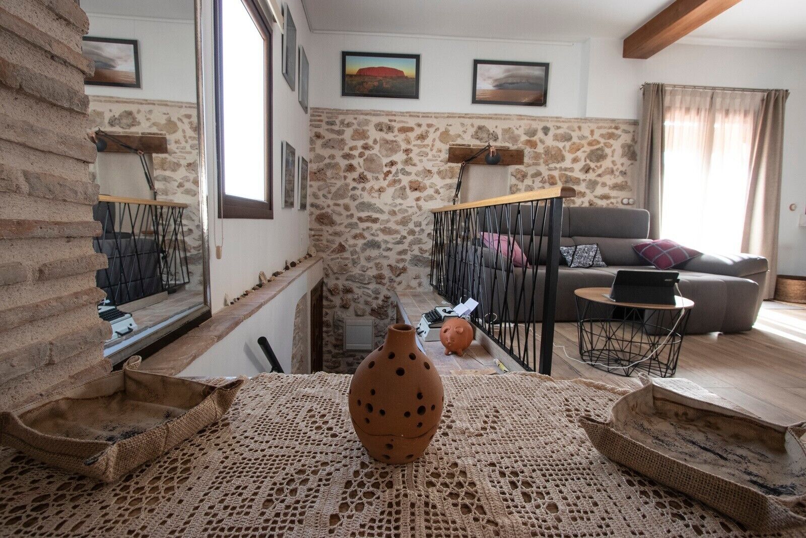 A living room with a stone wall, a sofa, a coffee table, and a laptop.
