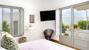 Een slaapkamer met een bed, een televisie, een stoel en uitzicht op de omgeving.