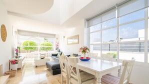 A bright living room with a dining area, large windows, and a view of greenery. - Holiday Home 'Marc 6' with Private Pool, Wi-Fi and Air Conditioning (Can Picafort)