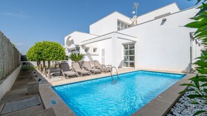A swimming pool with lounge chairs, a small tree, and a white building with a flat roof. - Holiday Home 'Marc 6' with Private Pool, Wi-Fi and Air Conditioning (Can Picafort)