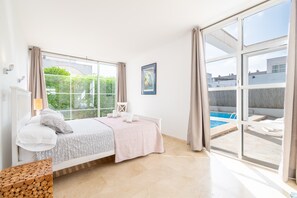 Un dormitorio con un ventanal grande, una cama, una mesita de noche y vistas a una piscina.