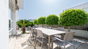 An outdoor patio with a table and chairs, surrounded by neatly trimmed bushes and a palm tree. - Holiday Home 'Marc 6' with Private Pool, Wi-Fi and Air Conditioning (Can Picafort)