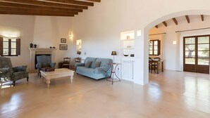 A spacious living room with a fireplace, a blue sofa, and a coffee table. - Country House 'Calma' with Mountain View, Private Pool and Wi-Fi (Illes Balears)