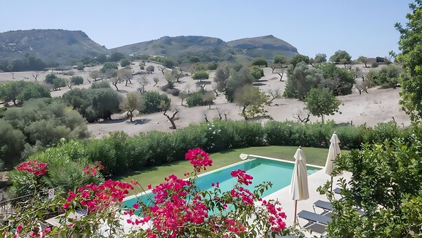A pool with a view of a hilly landscape, surrounded by greenery and flowers. - Country House 'Calma' with Mountain View, Private Pool and Wi-Fi (Illes Balears)