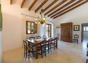 Uma sala de jantar com uma mesa e cadeiras de madeira, um candelabro e um armário grande de madeira.