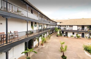 A multi-story building with balconies, potted plants, and outdoor seating areas.