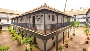 Un bâtiment à deux étages doté d’un balcon, entouré de plantes en pot.