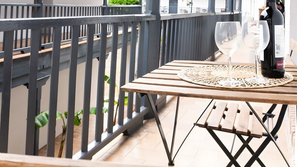 Un balcon avec une table, deux verres à vin et une bouteille de vin.