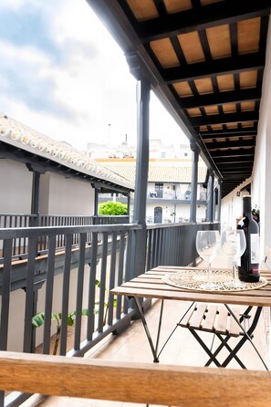 A balcony with a table, two wine glasses, and a bottle of wine.