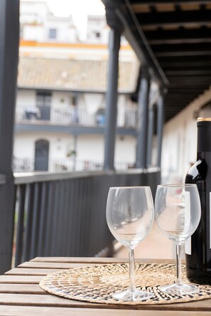 A balcony with two empty wine glasses and a bottle on a woven placemat.