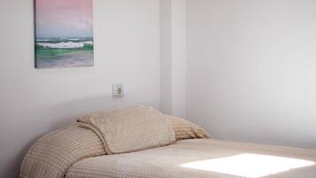 A bedroom with a bed, a painting, and a wall socket.
