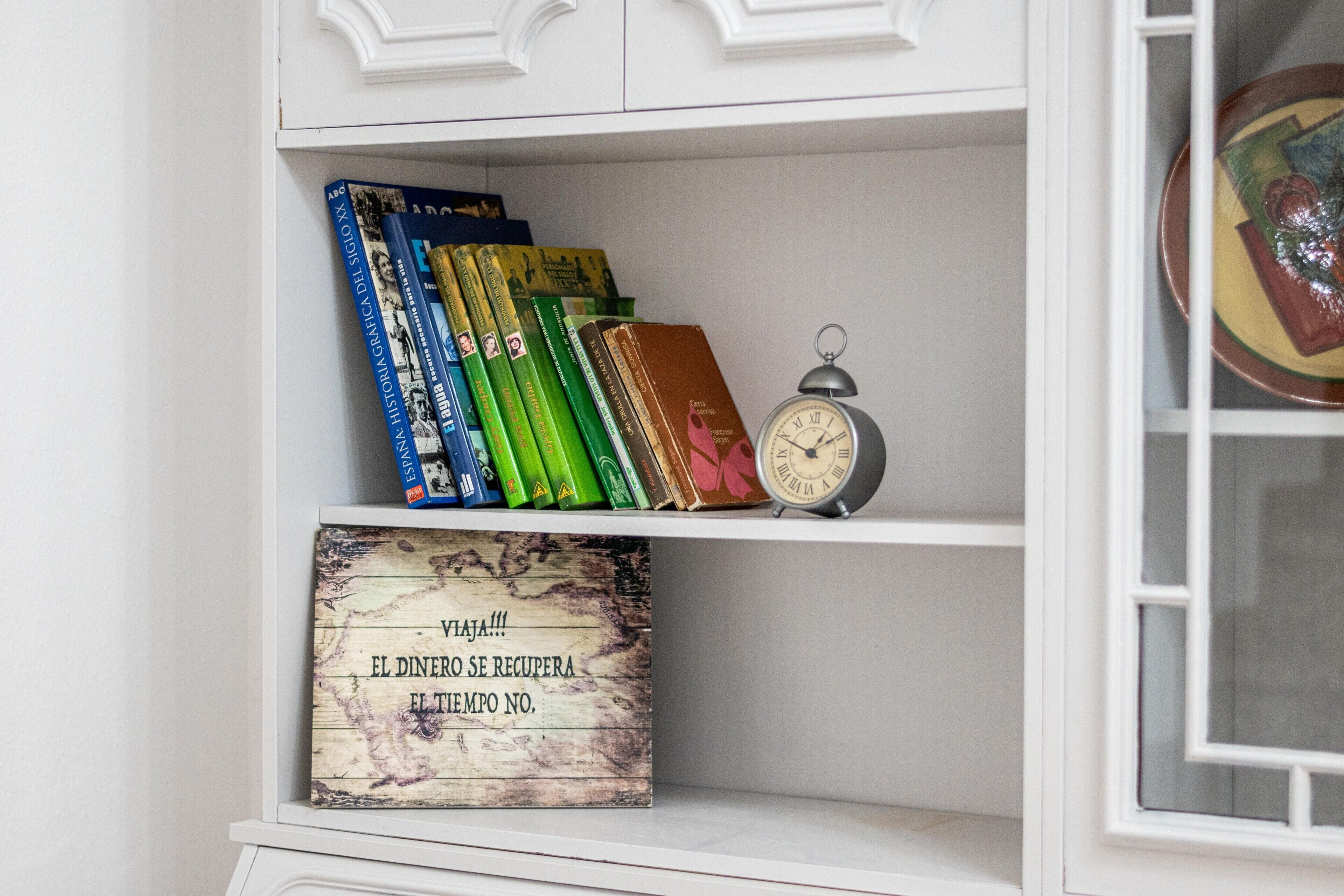 A bookshelf with books and a decorative plate.