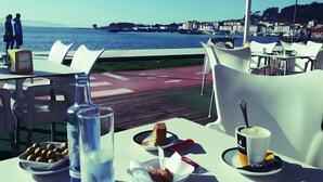 An outdoor dining area with tables, chairs, and a view of the water and cityscape. - Holiday Home 'Villa Lukita' with Sea Views, Wi-Fi and Air Conditioning (Cangas)