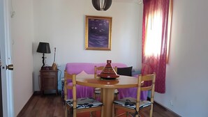 A dining area with a table, chairs, a lamp, a painting, and a window with curtains. - Holiday Home 'Villa Lukita' with Sea Views, Wi-Fi and Air Conditioning (Cangas)