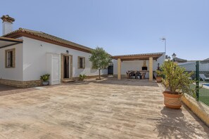 A courtyard with a tiled floor, a white building with a tiled roof, and potted plants. - Holiday Home 'Echizzo' with Private Pool, Wi-Fi and Air Conditioning (Chiclana de la Frontera)