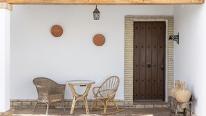 Eine Terrasse mit Korbmöbeln, einer Holztür und dekorativen Platten an der Wand.