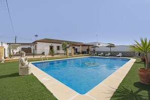 A swimming pool with a tiled edge, a Buddha statue, and a house with a tiled roof. - Holiday Home 'Echizzo' with Private Pool, Wi-Fi and Air Conditioning (Chiclana de la Frontera)