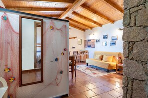 Ein Zimmer mit Holzboden, Steinwand, Spiegel, Klettergriffen, einer Couch und einem Essbereich.