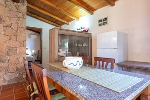 Eine Küche mit Granitarbeitsplatten, Holzstühlen, einem weißen Kühlschrank und einer Steinwand.