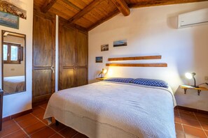Ein Schlafzimmer mit Bett, Holzschrank und einer an der Wand befestigten Ablage.