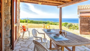Une terrasse extérieure avec un sol en pierre, des meubles en bois et une vue sur la mer.