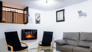 A living room with a fireplace, two chairs, a sofa, and wall art.